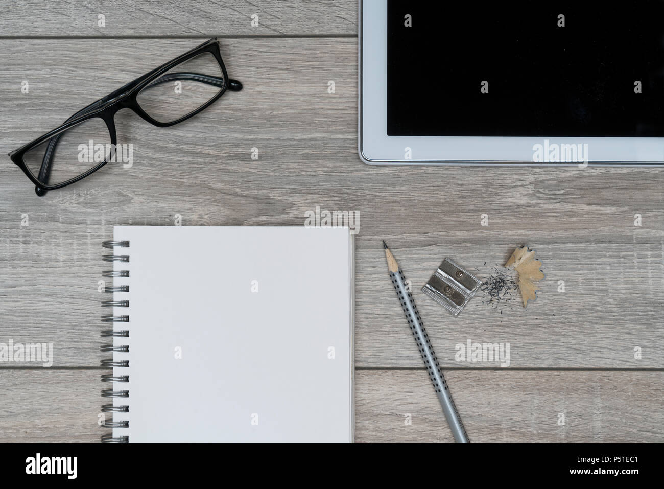 a clipboard, a pair of glasses and a tablet on a wooden table Stock Photo