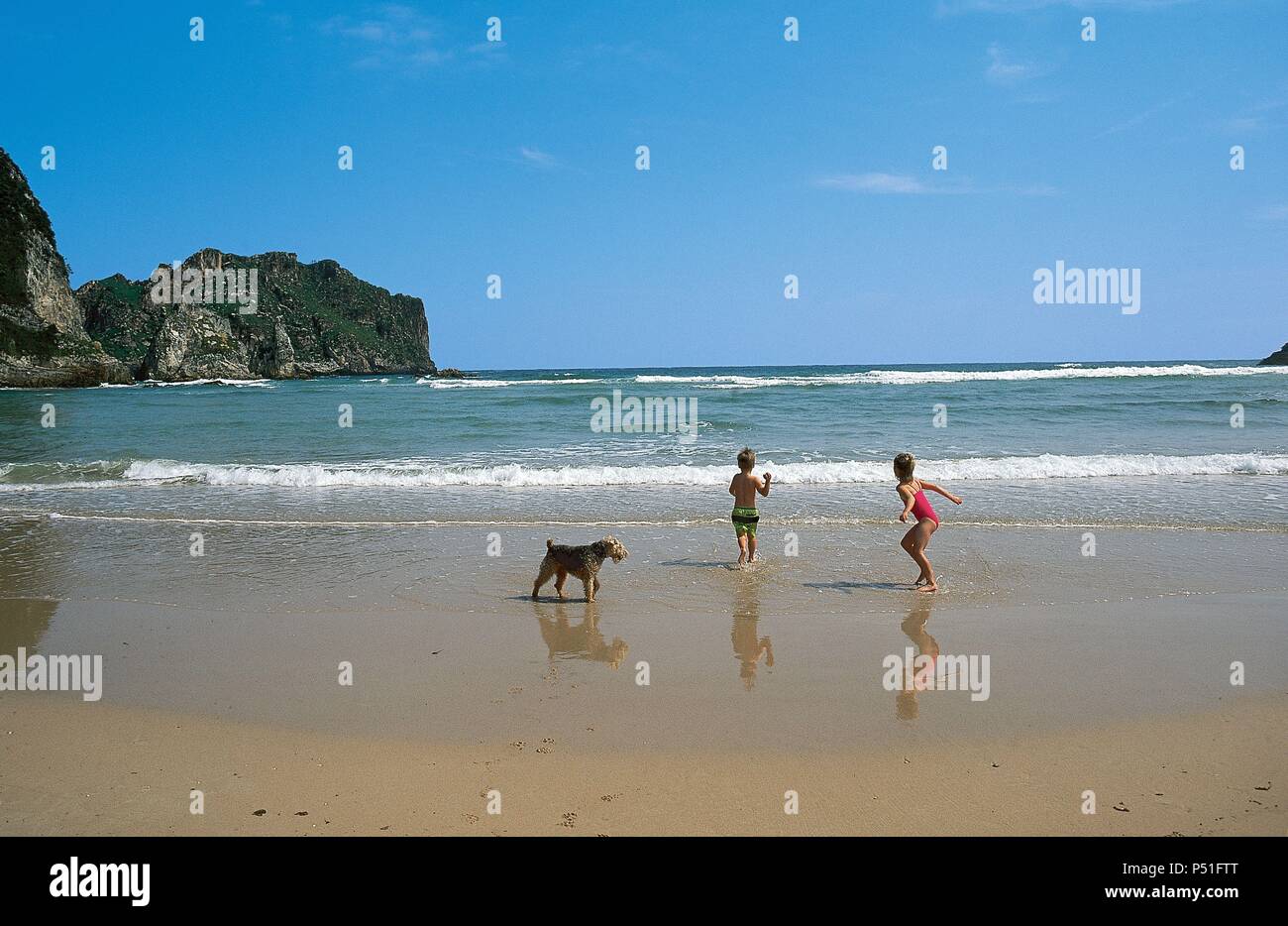 Niños jugando a la orilla del mar en la PLAYA DE LA FRANCA, en la costa oriental asturiana. LA FRANCA. Asturias. España. Stock Photo