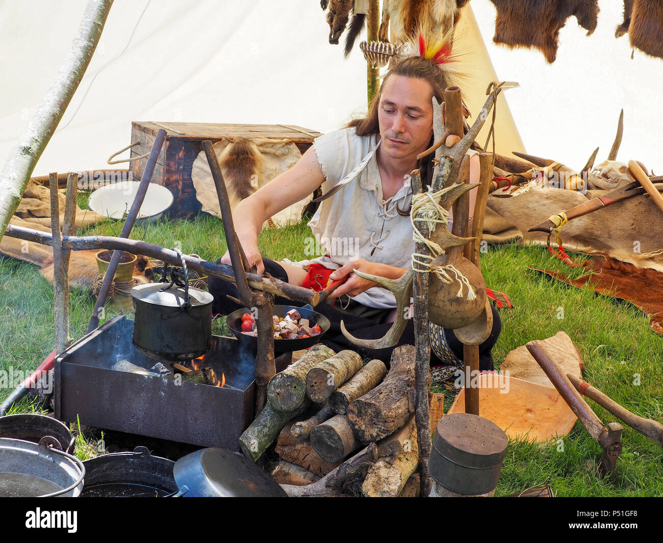 Documentary editorial image. ELBEUF, FRANCE - JUNE 9, 2018. An unidentified man dressed like indian from america is cooking the lunch on the fire wood Stock Photo
