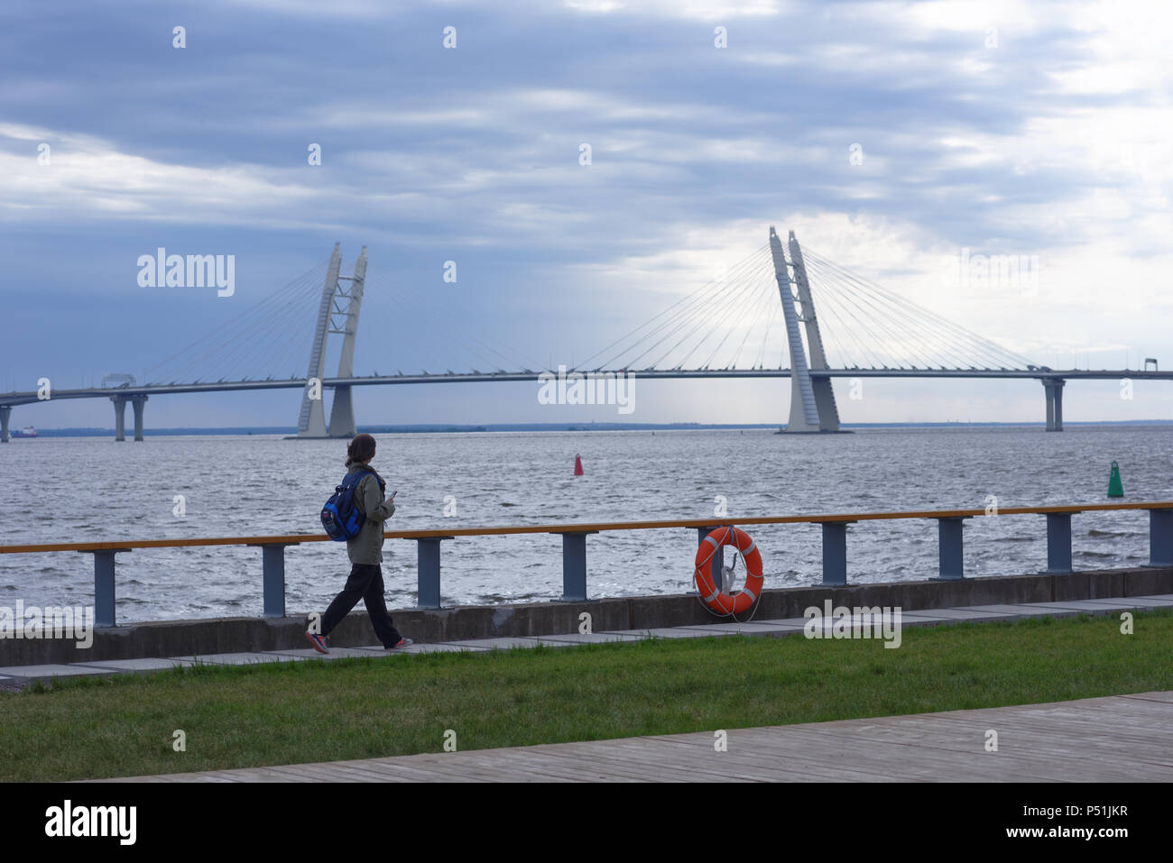 St. Petersburg, Russia - June 1, 2018: Girl walking at Neva waterfront against cable-stayed bridge over the Korabelny Fairway in Saint Petersburg. The Stock Photo