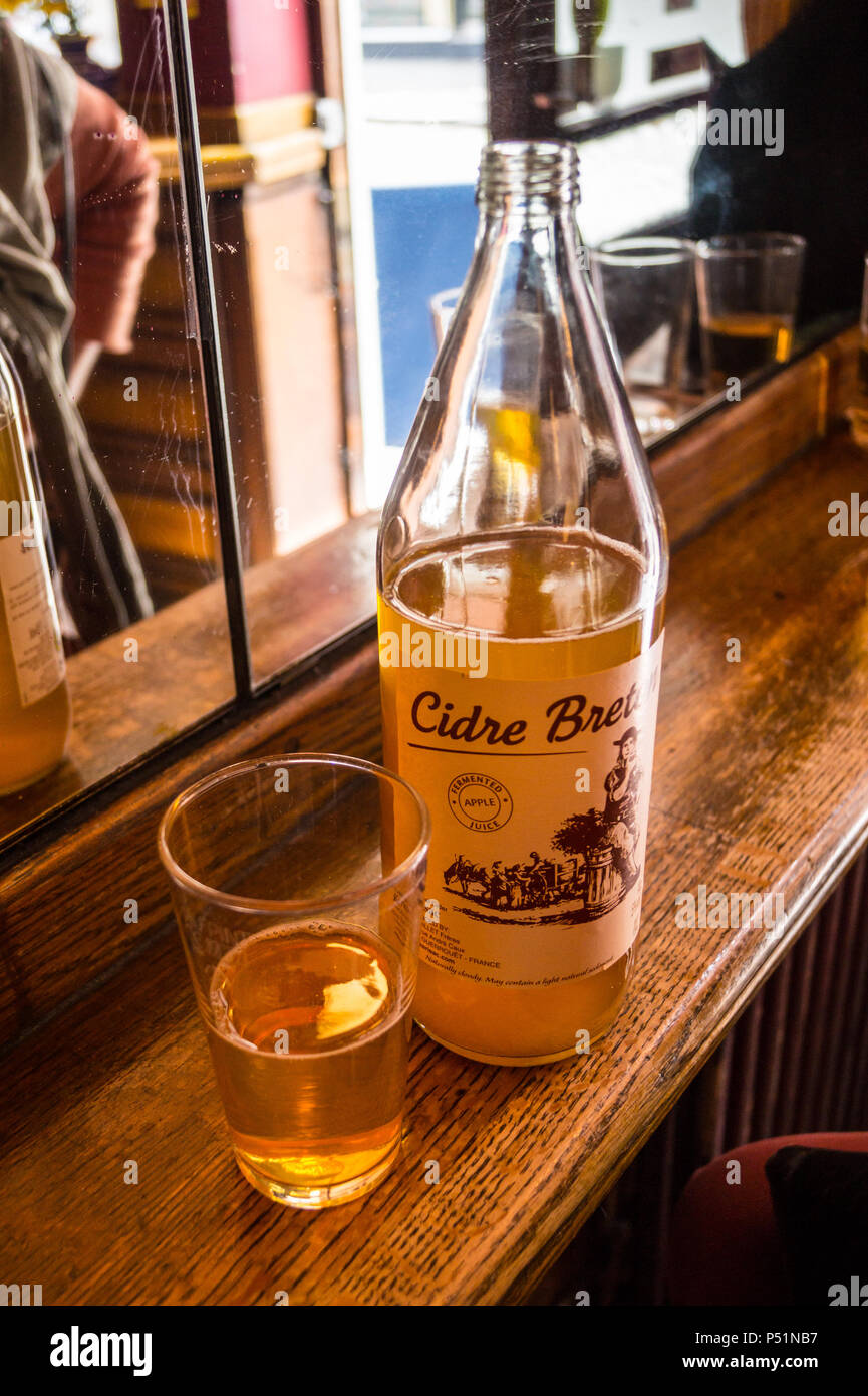 A glass and bottle of breton cider on a bar at the French House bar