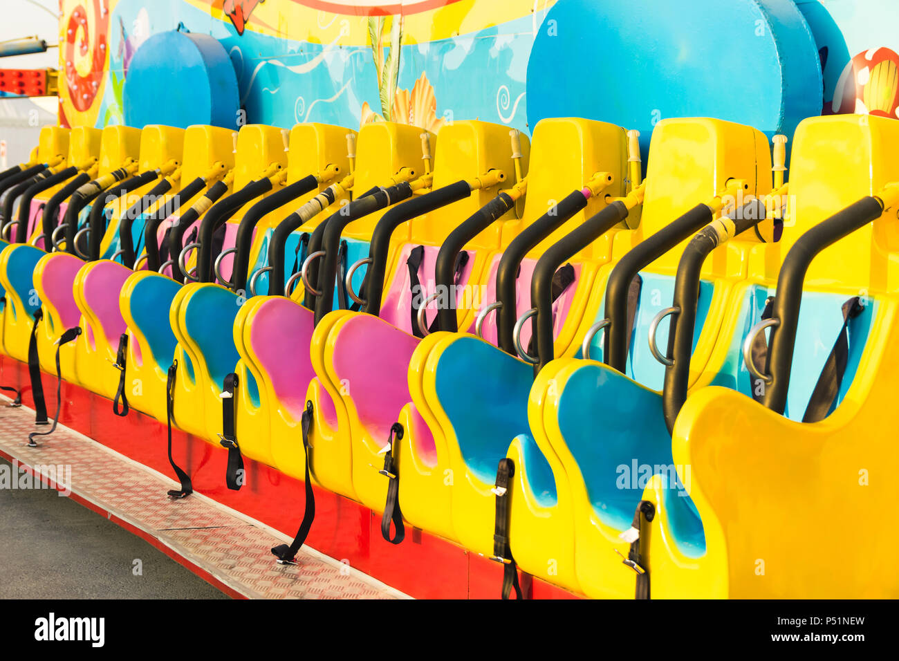 Row of colorful empty seats of a fair ride, roller coaster Stock Photo