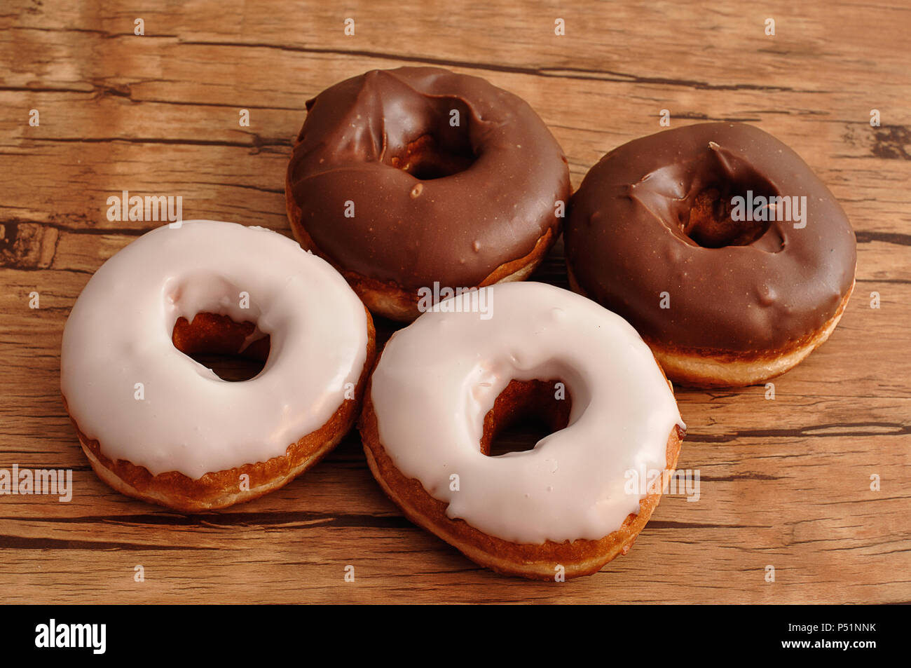 Four doughnuts displayed on a wooden table Stock Photo