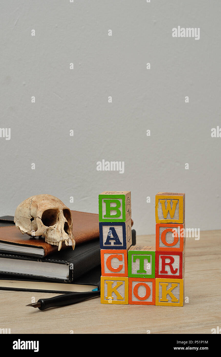 Back to work spelled in colorful blocks with a stack of books, a fountain pen and a monkey skull Stock Photo
