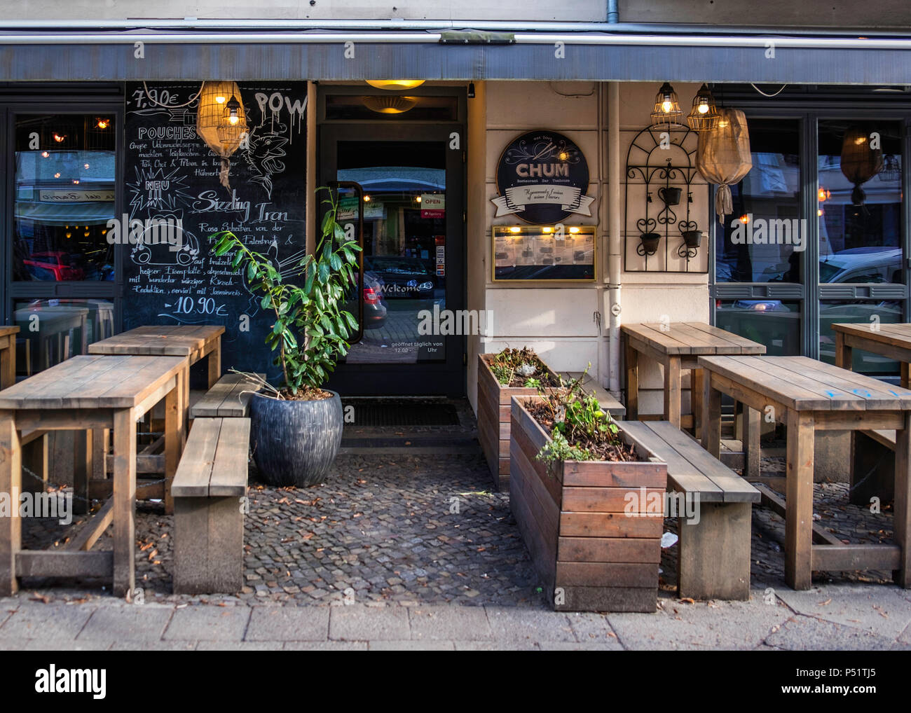 Berlin, Friedrichshain-Kreuzberg, Chum restaurant,bar & teahouse , Asian diner exterior with wooden tables on cobbled pavement Stock Photo