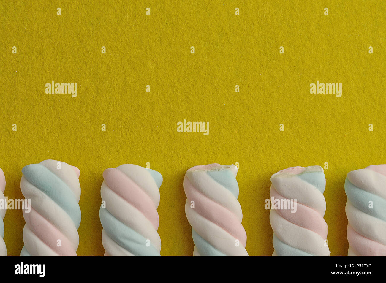A row of pastel colored marshmallows on a yellow background Stock Photo