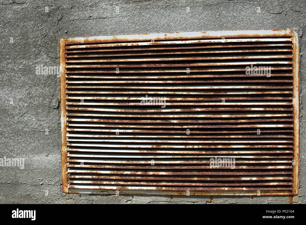 A brick wall with a rusty iron grille in it Stock Photo