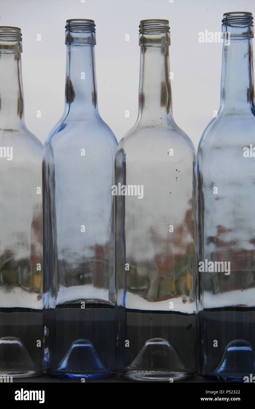 Row of old empty wine bottles on a window sill distorting the sun light