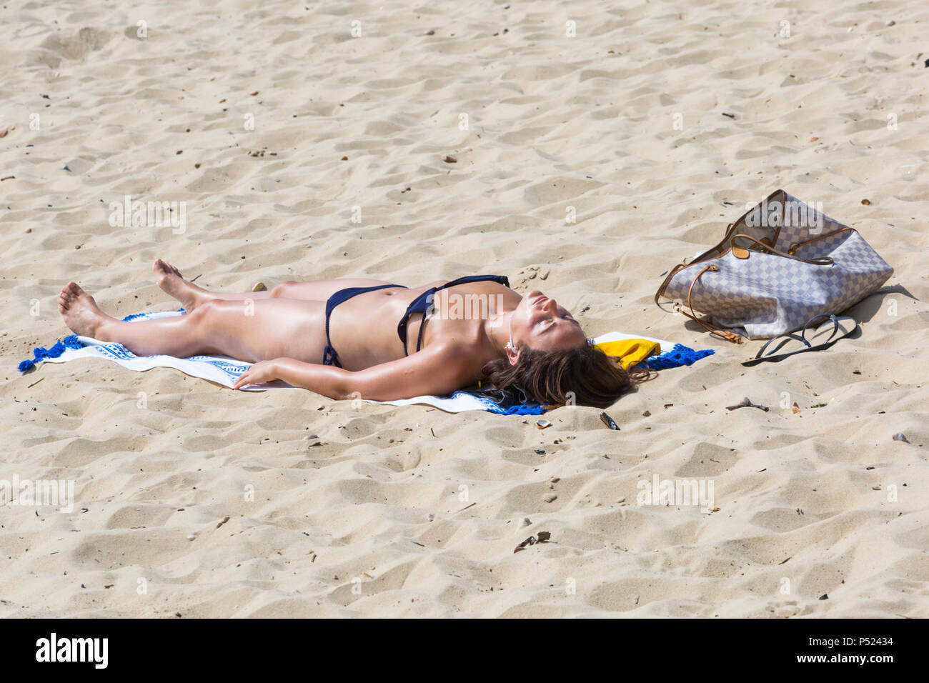Bournemouth, Dorset, UK. 24th June 2018. UK weather: another lovely hot sunny day as visitors head to the seaside to make the most of the sunshine as temperatures rise for the heatwave. Woman sunbather in bikini soaking up the sun on Bournemouth beach - sunbathing. Credit: Carolyn Jenkins/Alamy Live News Stock Photo