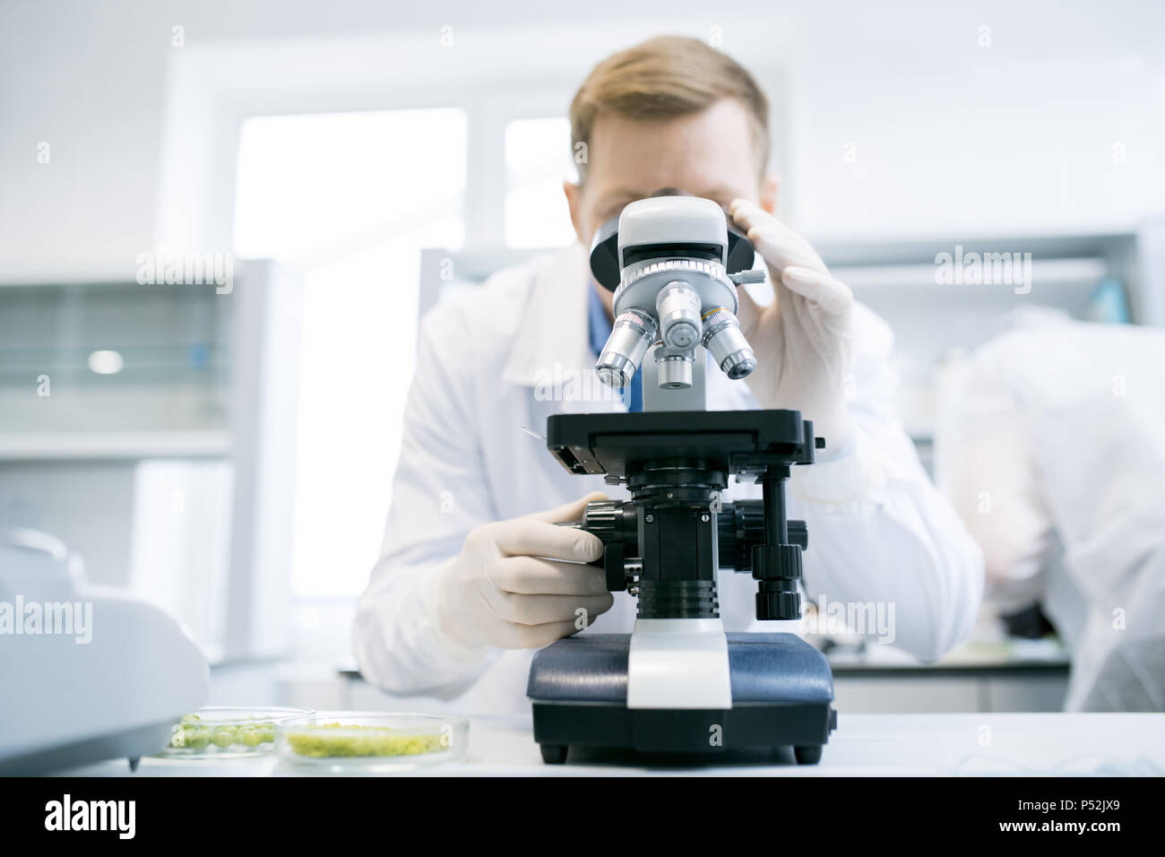 Man looking at microscope in laboratory Stock Photo