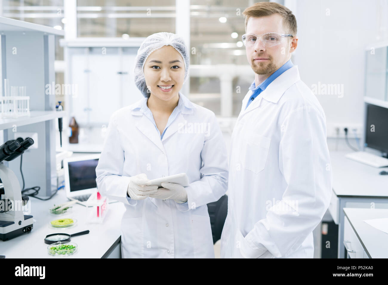 Smiling microbiologists standing in laboratory with tablet Stock Photo
