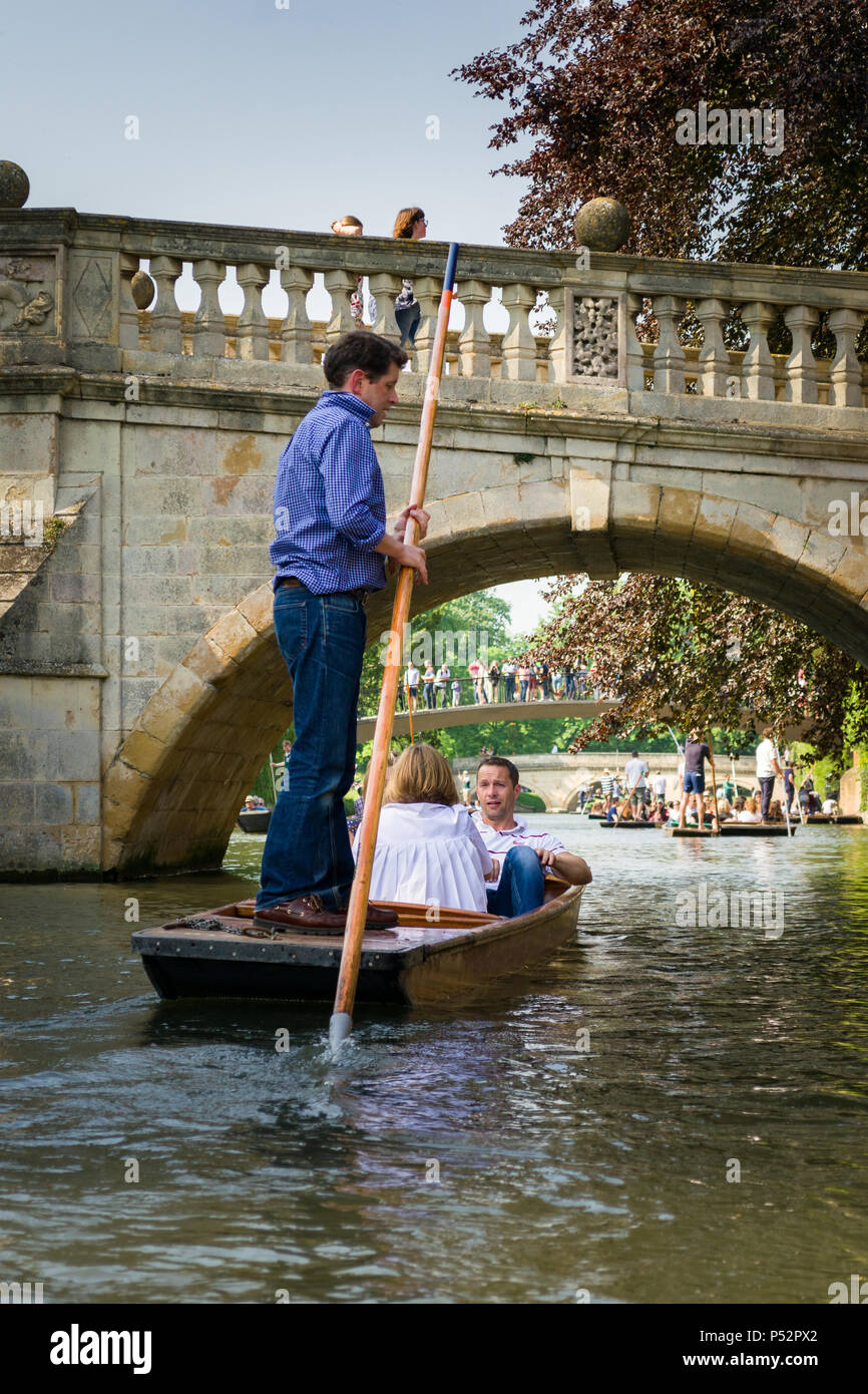 People on punt boats punting on the river Cam as people walk on a bridge beside it on a sunny Summer afternoon, Cambridge, UK Stock Photo