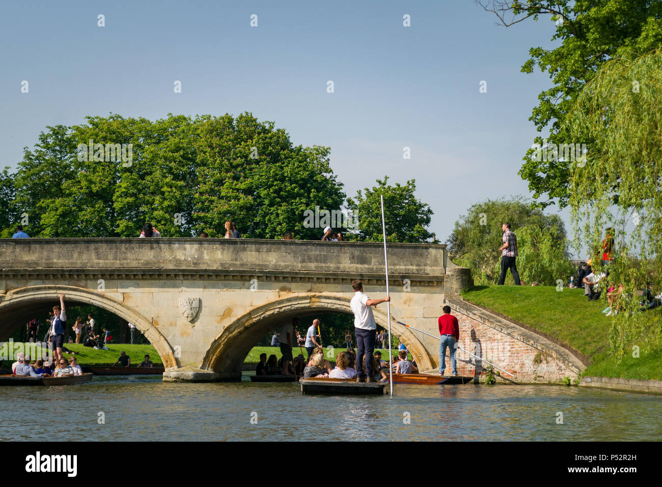 People on punt boats punting on the river Cam near a stone bridge on a sunny Summer afternoon, Cambridge, UK Stock Photo