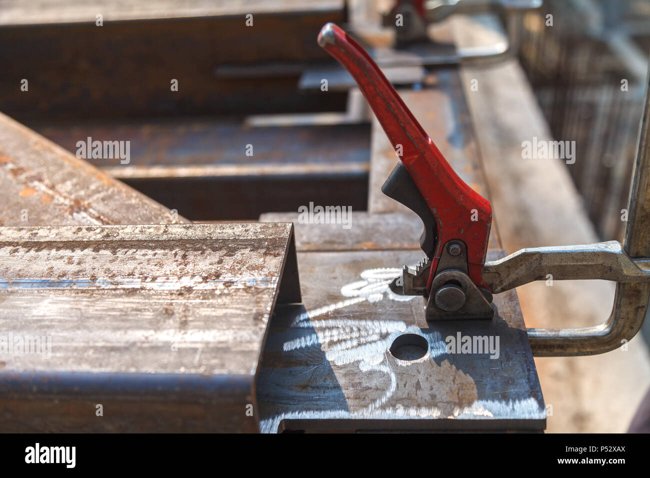 The clamping metal clamp with a red handle is mounted on a metal plate