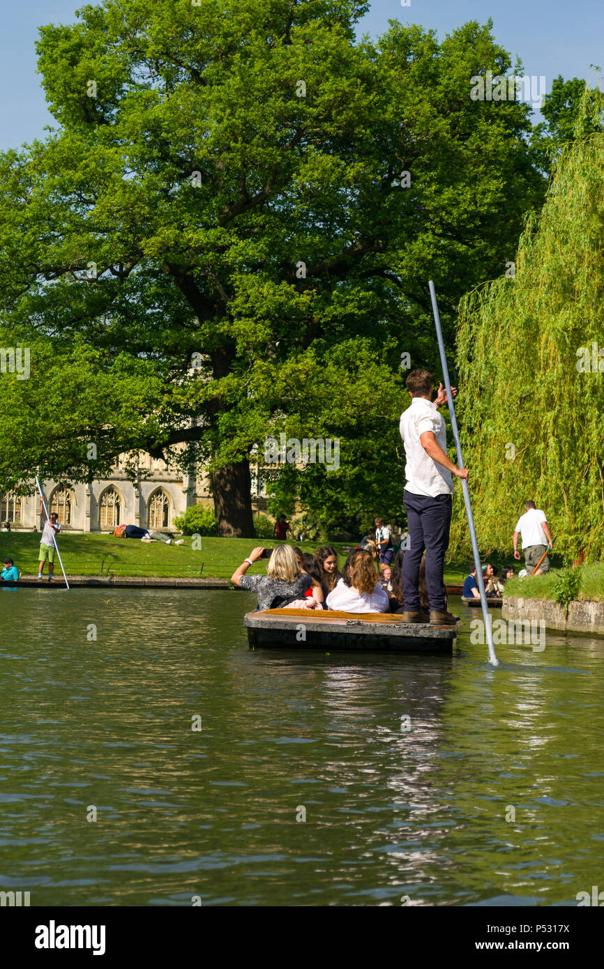 People on punt boats punting on the river Cam as people walk alongside it on a sunny Summer afternoon, Cambridge, UK Stock Photo