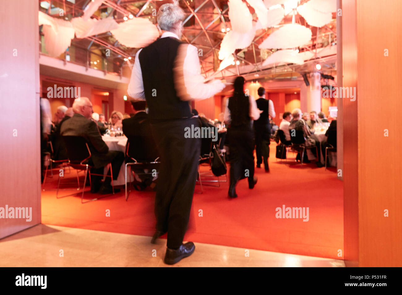 Berlin, Germany - Service staff in elegant wardrobe while applying the food at a festive evening event. Stock Photo