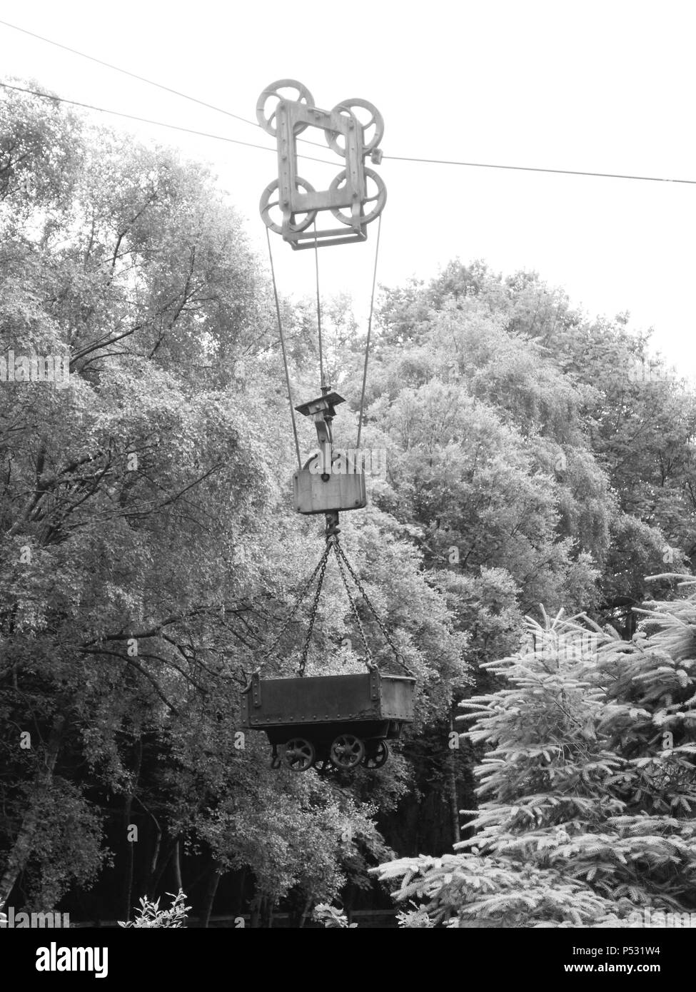 vintage mine cart suspended on a chain above a lake Stock Photo