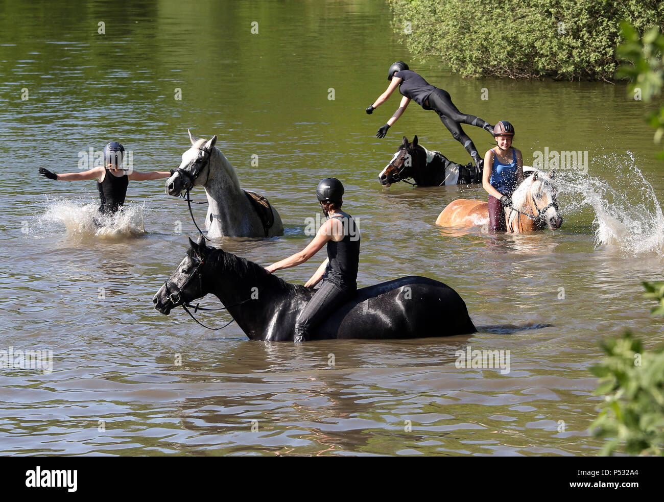 Oberoderwitz, Saxony, Germany - Girls jump from their horses into a lake Stock Photo