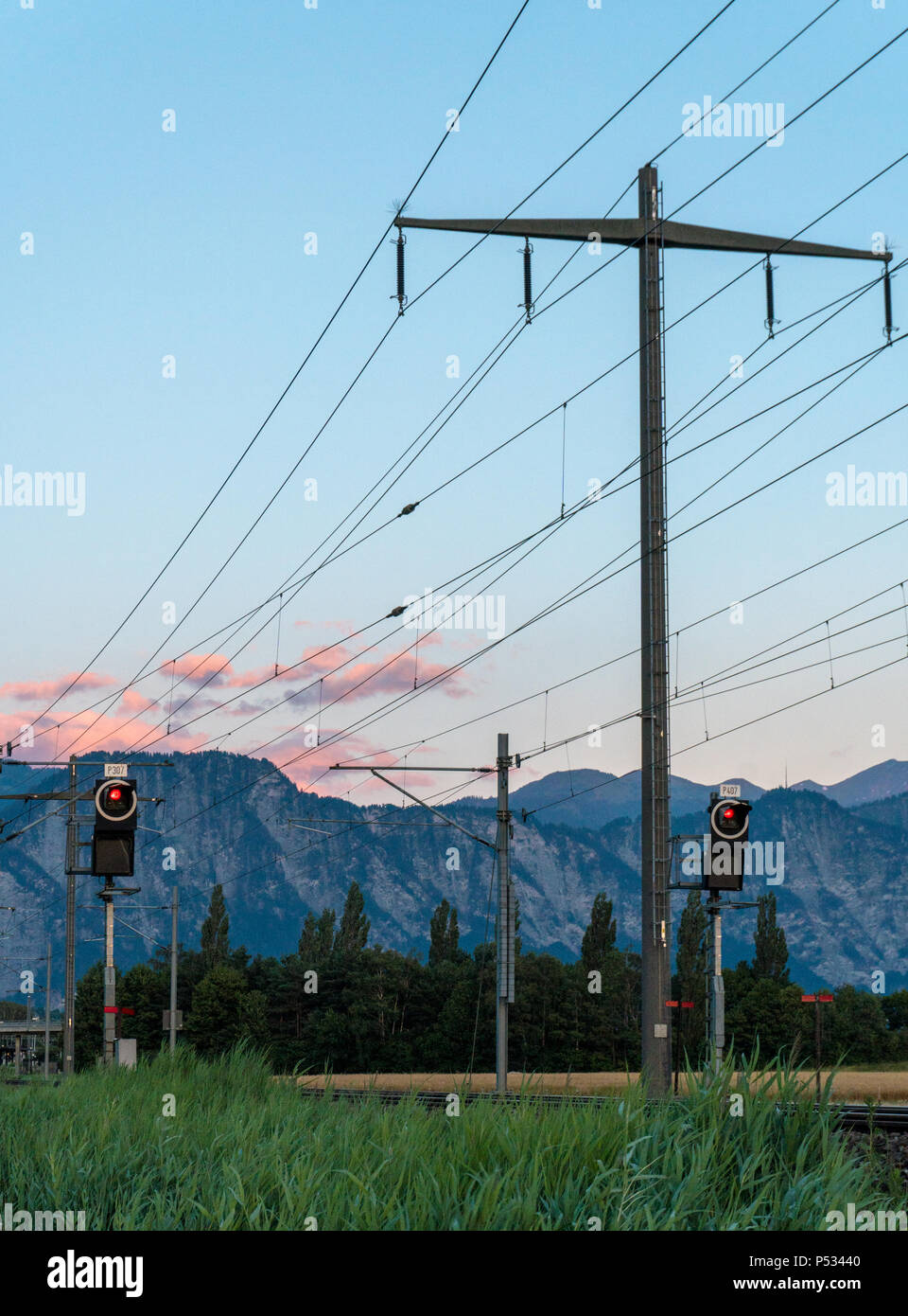 train tracks with red lights in a mountain valley at sunset Stock Photo