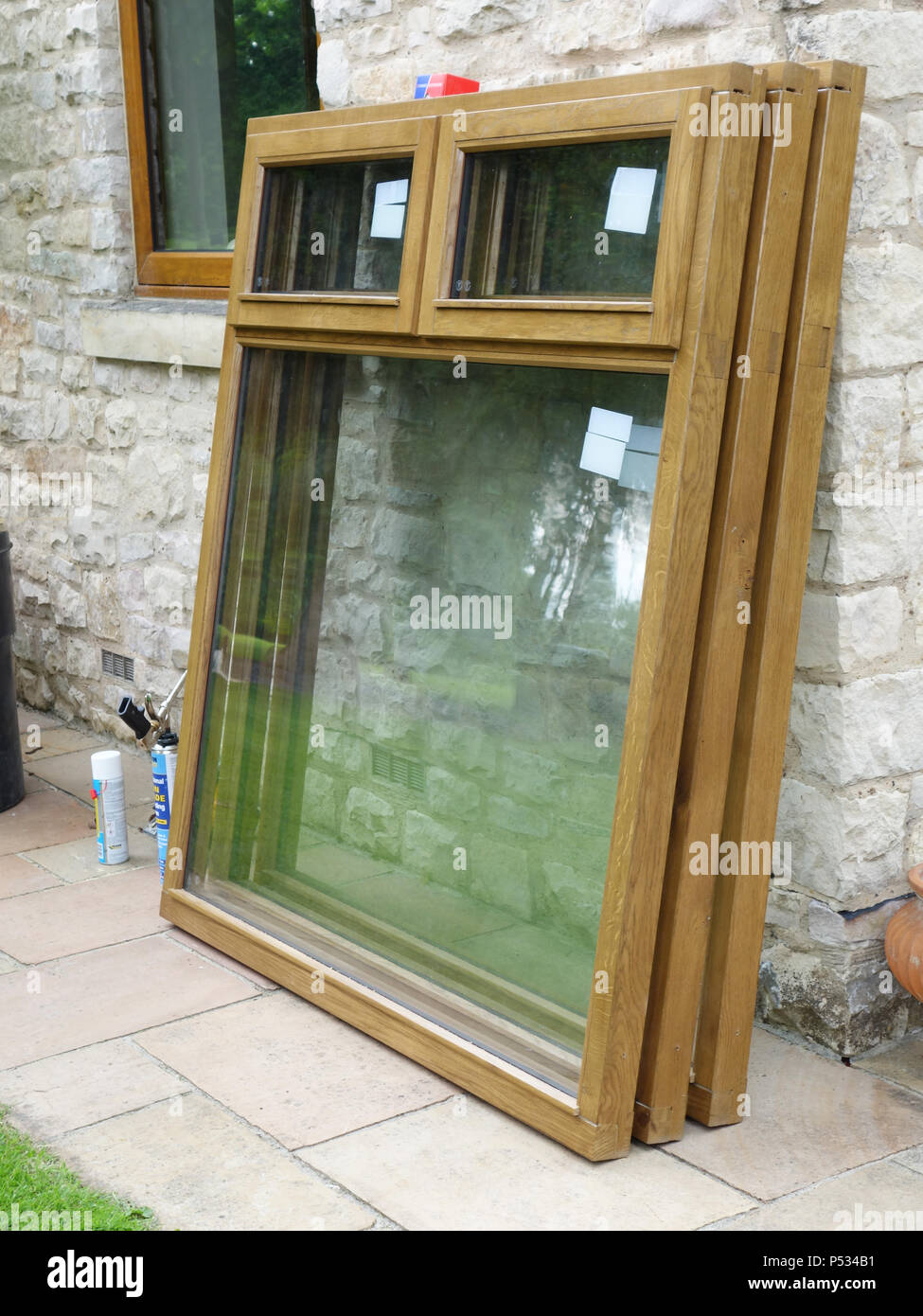 Three new double glazed solid oak window frames to be installed and replace old uPVC plastic wood effect window frames in a home Stock Photo