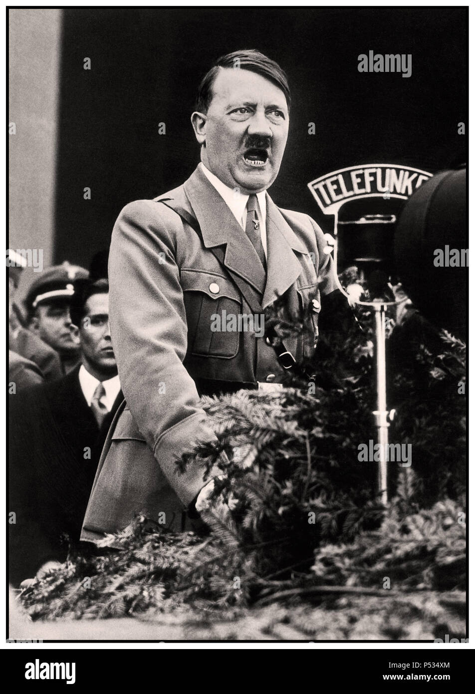 1930's Adolf Hitler speech with Telefunken Radio Microphone broadcasting to the German Nation standing at speaker's platform podium at a Nazi party rally at Nuremberg Germany Stock Photo