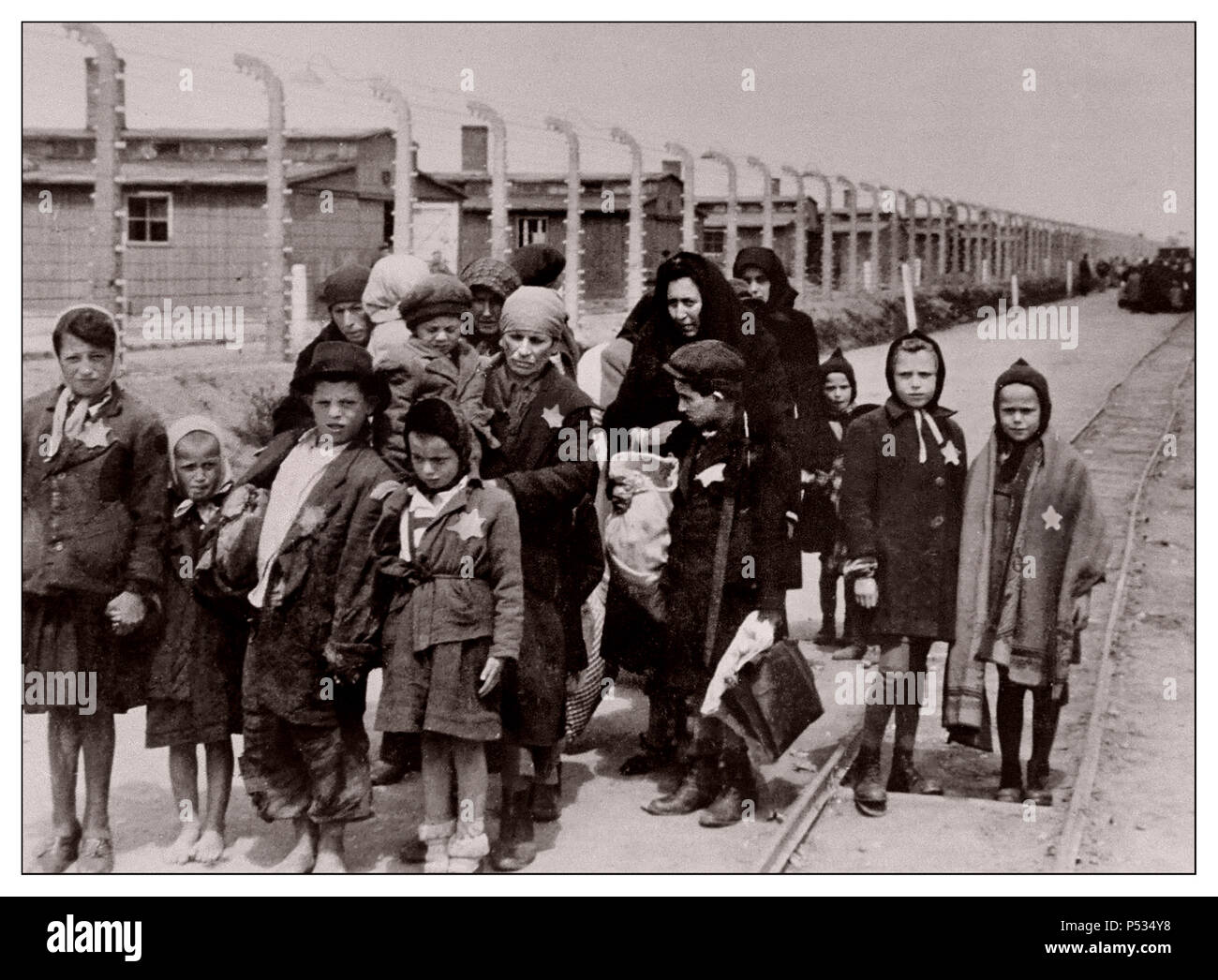 AUSCHWITZ Jewish children wearing Nazi designated yellow stars arrive in Auschwitz-Birkenau.  A WW2 German Nazi Concentration & Extermination camp. Jewish children made largest group deported to the camp. They were usually sent there along with adults, beginning in early 1942, as part of the “final solution of the Jewish question”—the total destruction of the Jewish population of Europe...Auschwitz concentration camp was a network of German Nazi concentration camps and extermination camps built and operated by the Third Reich in Polish areas annexed by Nazi Germany during World War II. Stock Photo