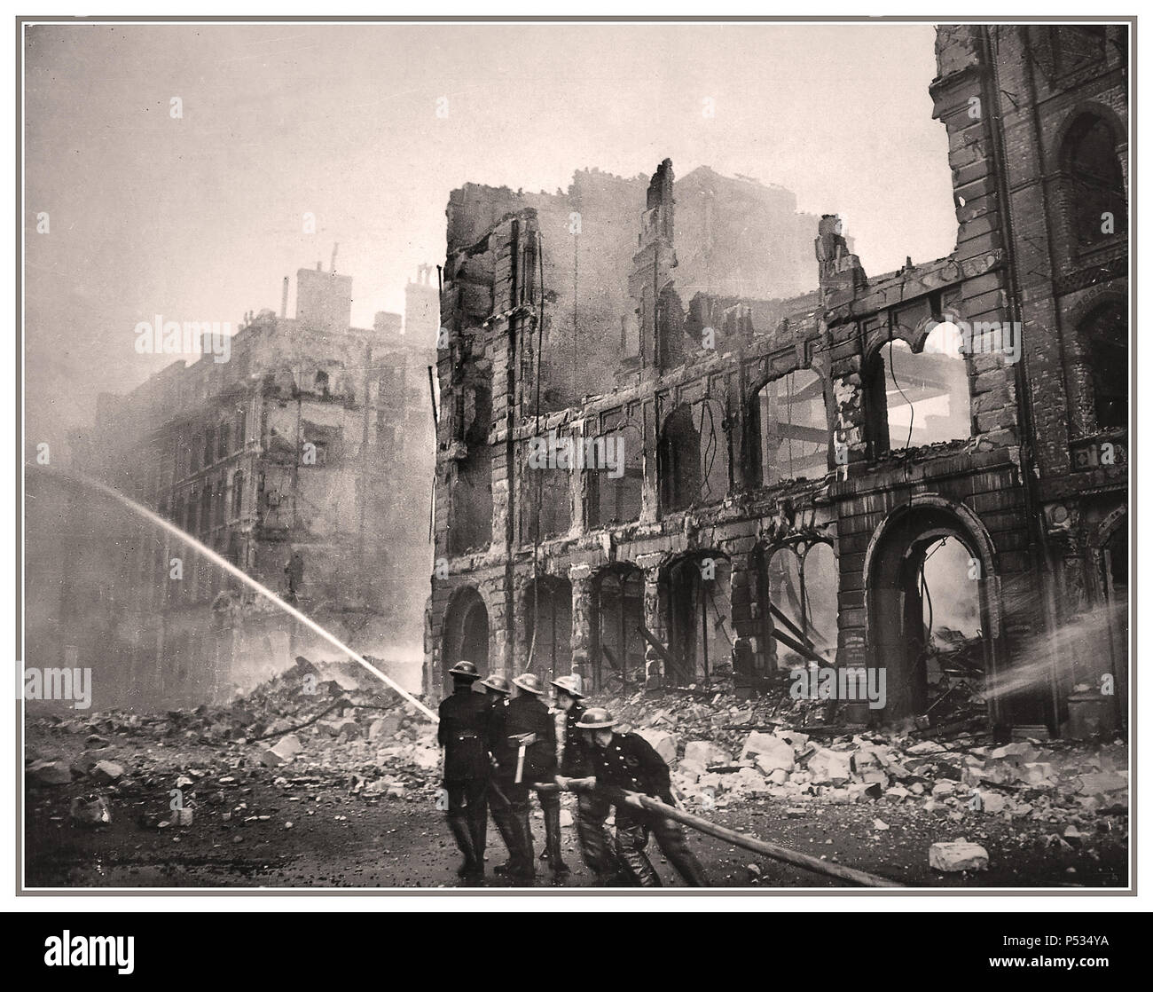 1940 London WW2 Blitz Bombing City Centre brave courageous British Fireman Firemen Firefighters with hose fighting fires and damping down after a Nazi Germany terror bombing raid. Central London City buildings in ruins with danger of imminent collapse London UK Stock Photo