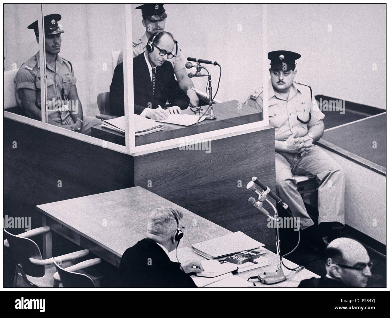 1961 Defendant Adolf Eichmann German Nazi War Criminal in reinforced glass booth, takes notes during his trial in Jerusalem. He was in charge of transporting millions of European Jews to death camps.The glass booth in which Eichmann sat was erected to protect him from assassination. He was found guilty convicted and the death sentence was passed and duly carried out Stock Photo