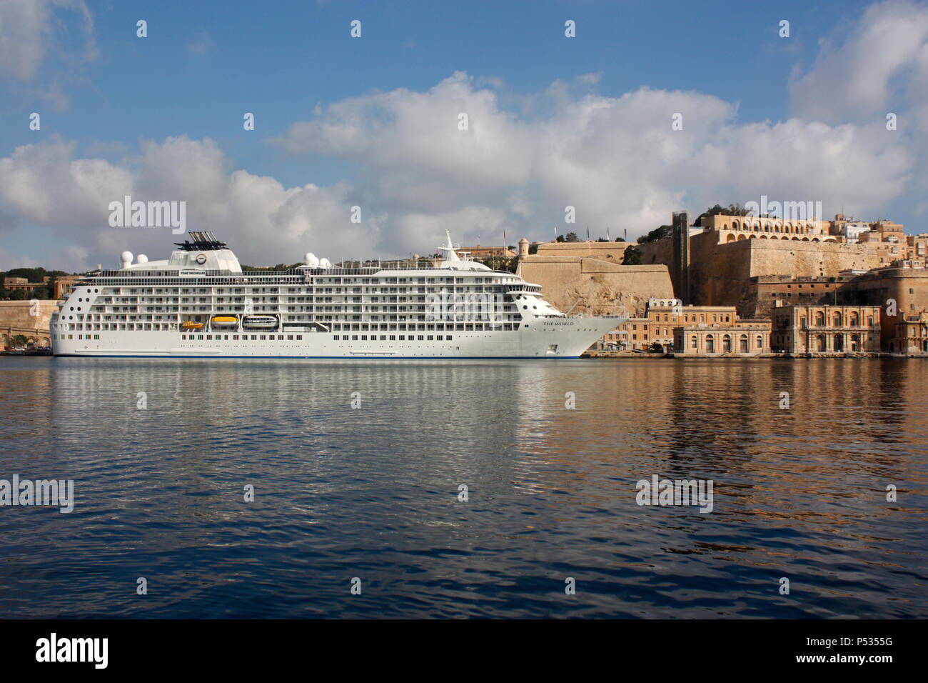 The residential cruise ship The World beneath the walls of Valletta in Malta's Grand Harbour. Travel and tourism in the Mediterranean Sea. Stock Photo