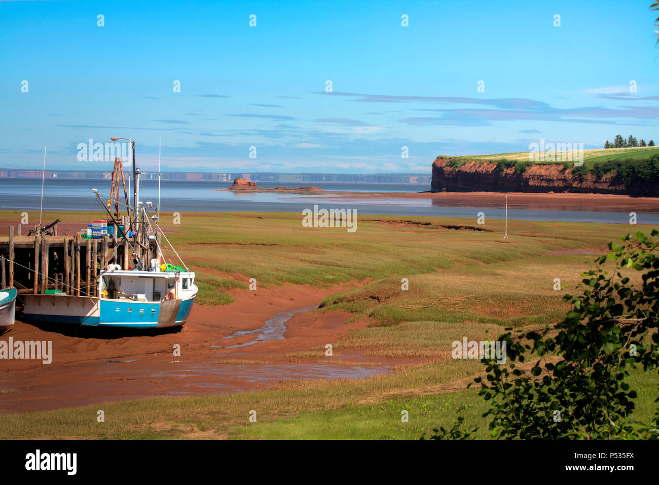 Fishing boats sit on the ocean floor during low tide. The tide rises ...