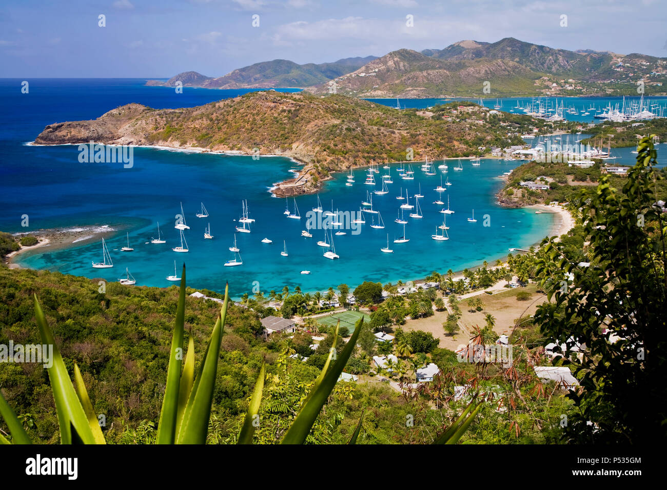Dozens of sailboats and yachts in the little blue green harbour in tropical Antigua Stock Photo