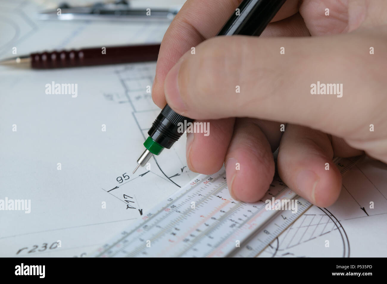 Engineer holding technical pen and works on a hand drawn technical drawing, sliderule Stock Photo