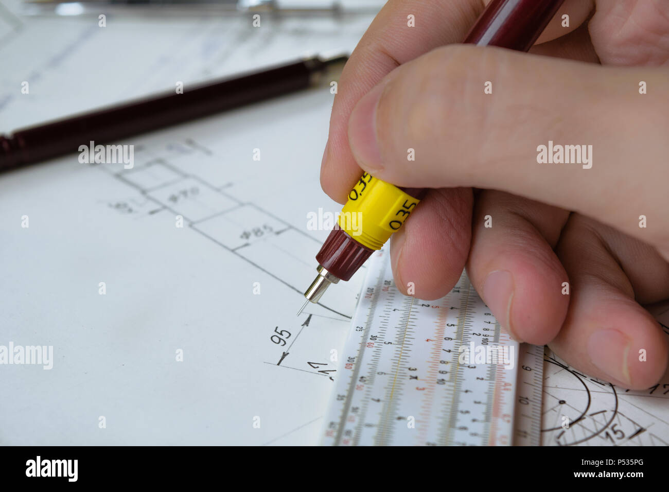 Engineer holding technical pen and works on a hand drawn technical drawing, sliderule Stock Photo