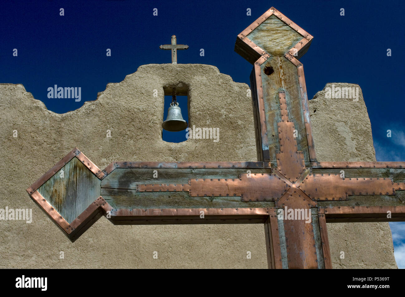 A metal and wooden cross adorns the courtyard of the San Lorenzo mission in Picurís Pueblo, NM. Stock Photo