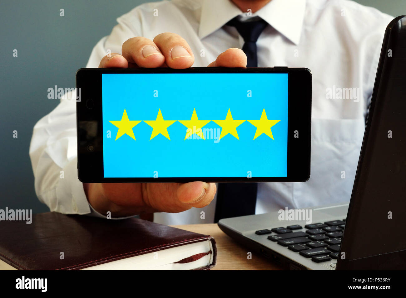 Man holding smartphone with five stars rating. Customer satisfaction. Stock Photo