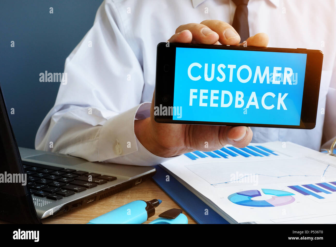 Busnessman holding phone with words Customer Feedback. Stock Photo