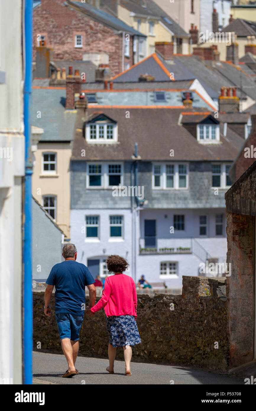 A couple holding hands as they stroll through the narrow streets at the picturesque Cornish fishing village of Cawand towards Kingsand, Cornwall, UK Stock Photo