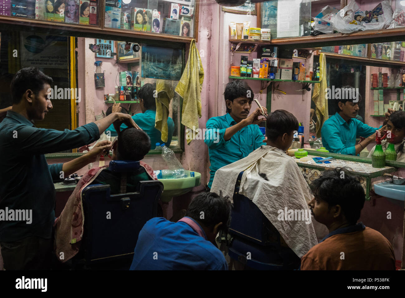 Barbers cutting hair at an outdoor barbershop in Kolkata, India