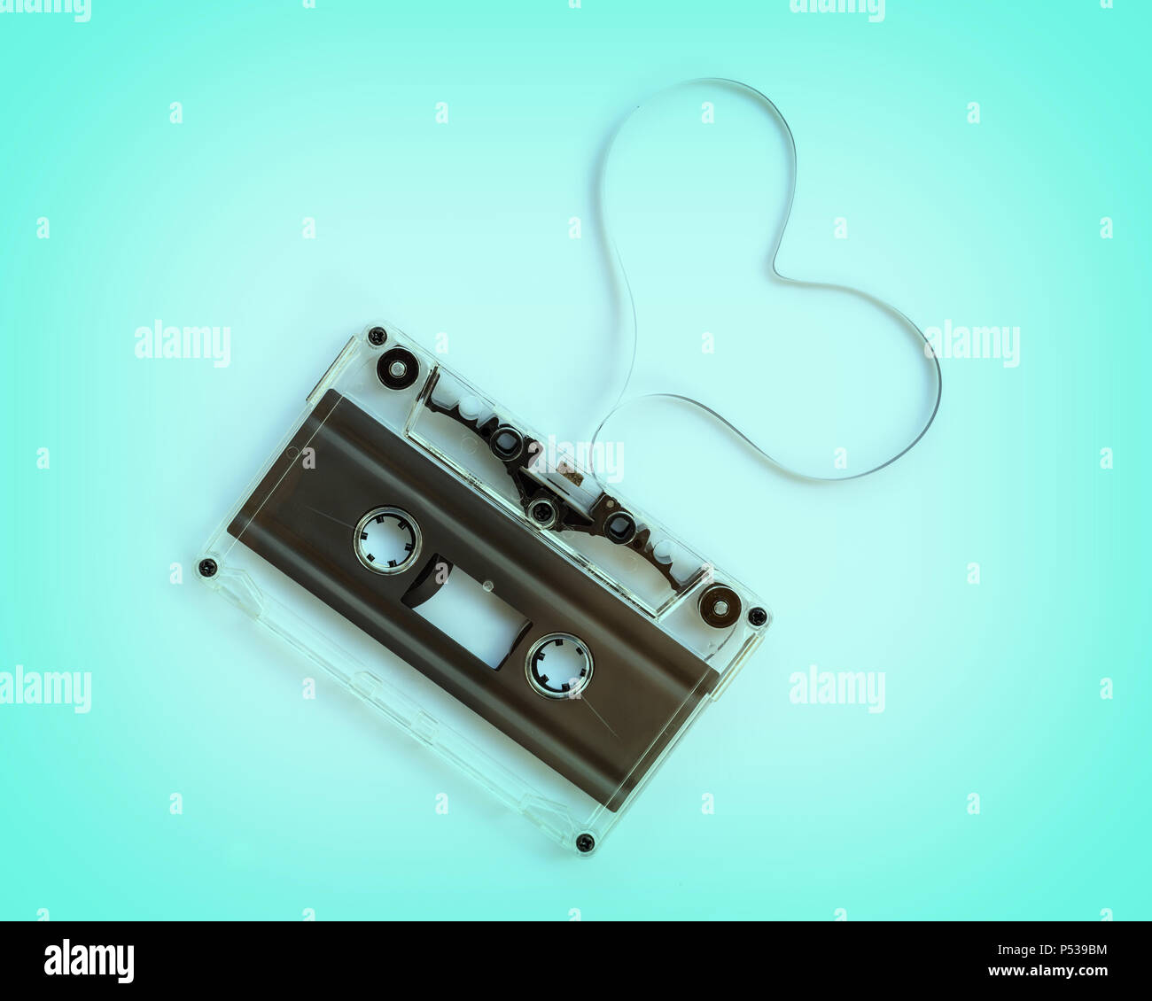 Translucent audio cassette with the magnetic tape in the shape of a heart  isolated on blue background, music love concept Stock Photo