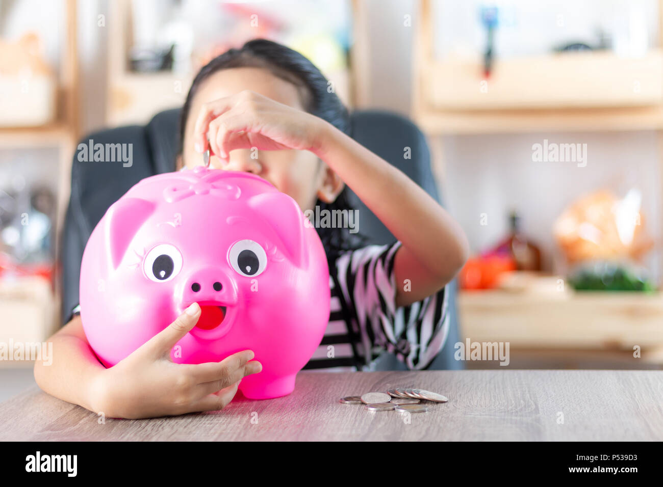 Asian little girl in putting coin in to piggy bank shallow depth of ...
