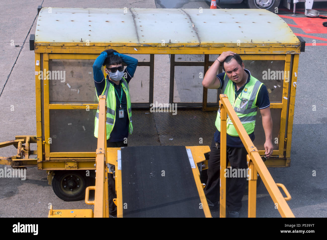 SAIGON, VIETNAM, DEC 13 2017, The men serve the conveyor belt and wait at the luggage going from the plane. Stock Photo