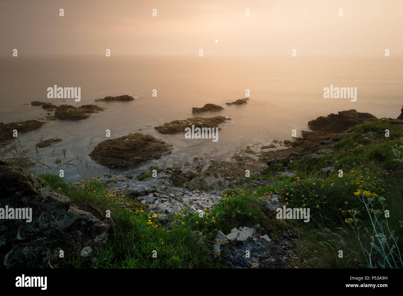 Sunset on the rocks, long exposure. Pointe du Grouin in France. Stock Photo