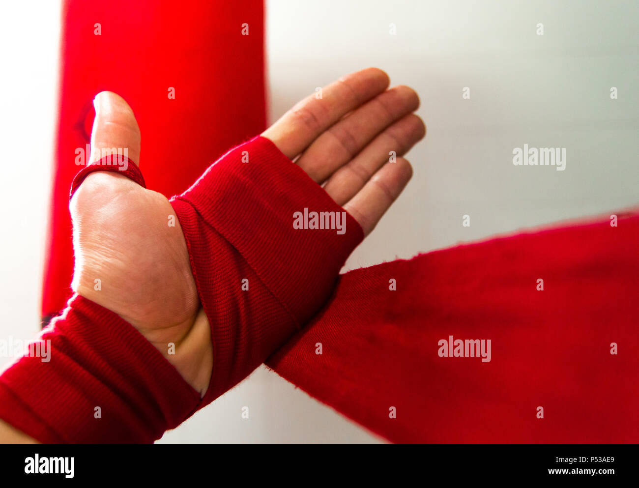 Closeup of young boy putting on red boxing bandages on his hands