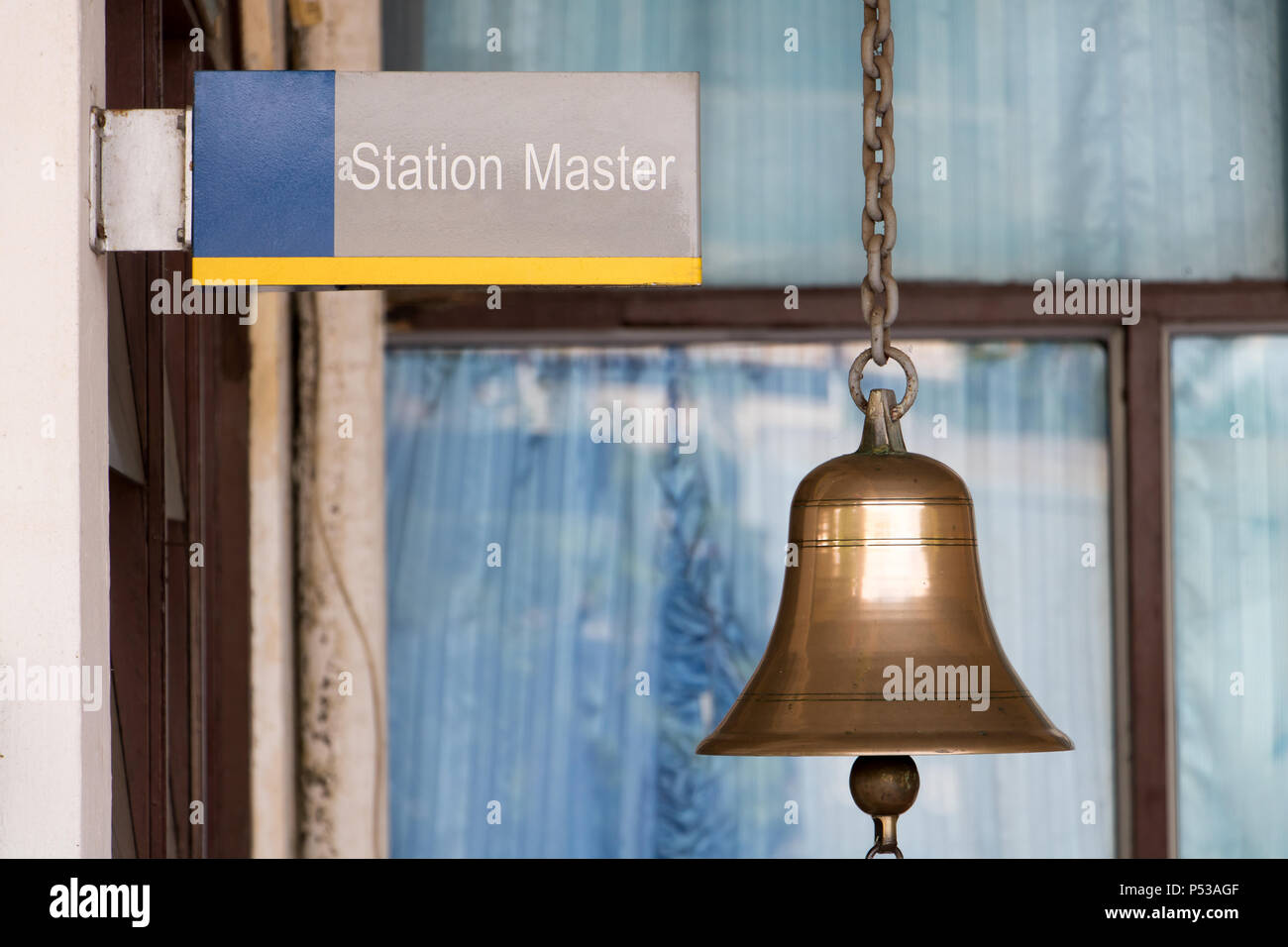 Closeup sign station master with a golden bell in train station. Traditional sound signaling on the platform at the railway station. Stock Photo