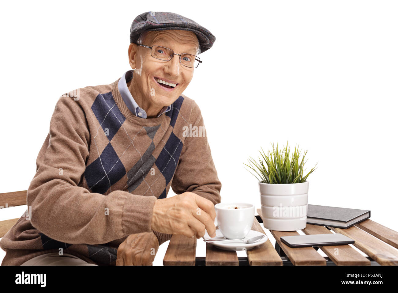 Elderly man sitting at a coffee table and smiling isolated on white background Stock Photo