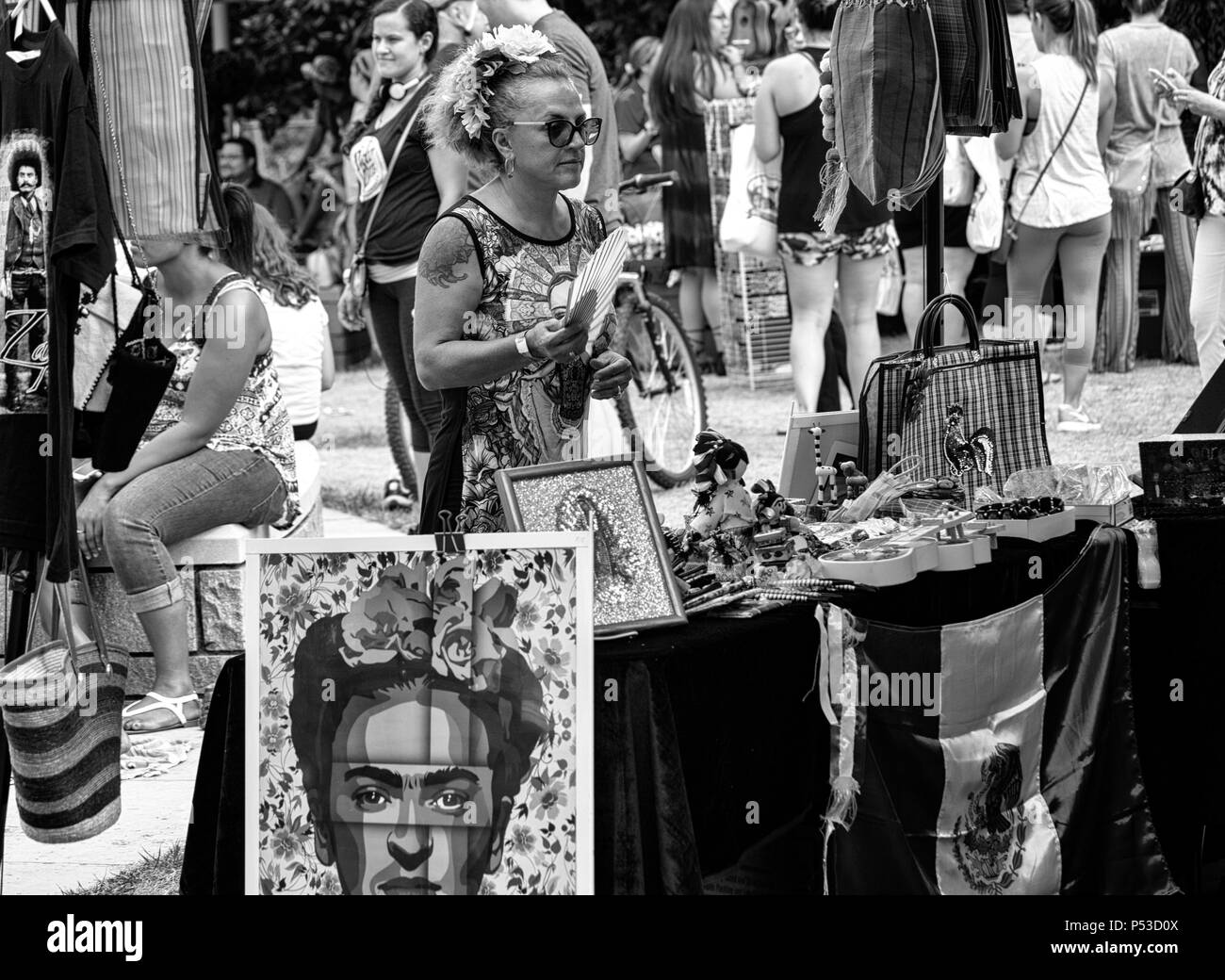 A female vendor fans herself in front of a poster of Frida Kahlo at the Hola Asheville Festival in Asheville, NC, USA Stock Photo