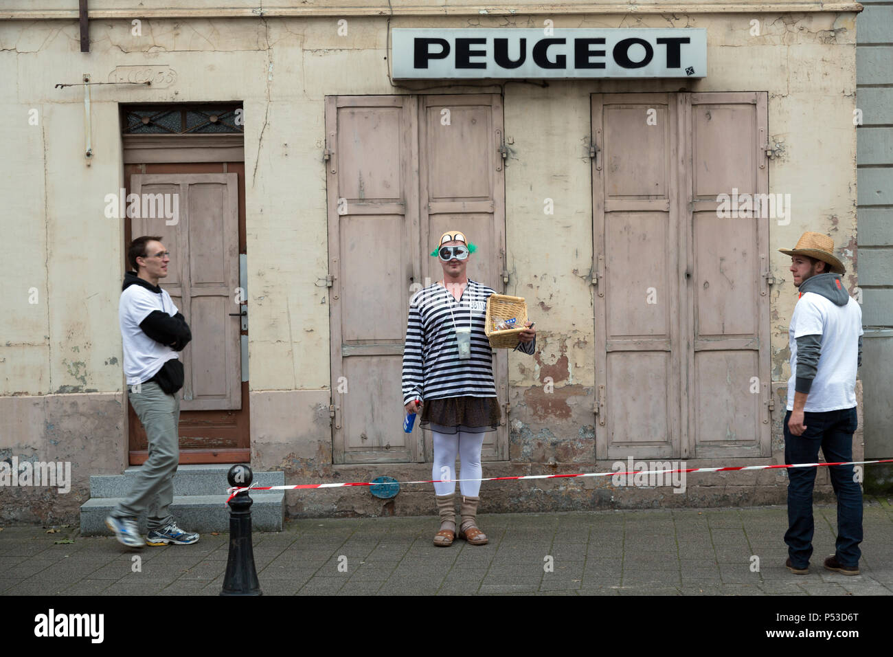 France - Street scene with disguised man and Peugeot lettering Stock Photo