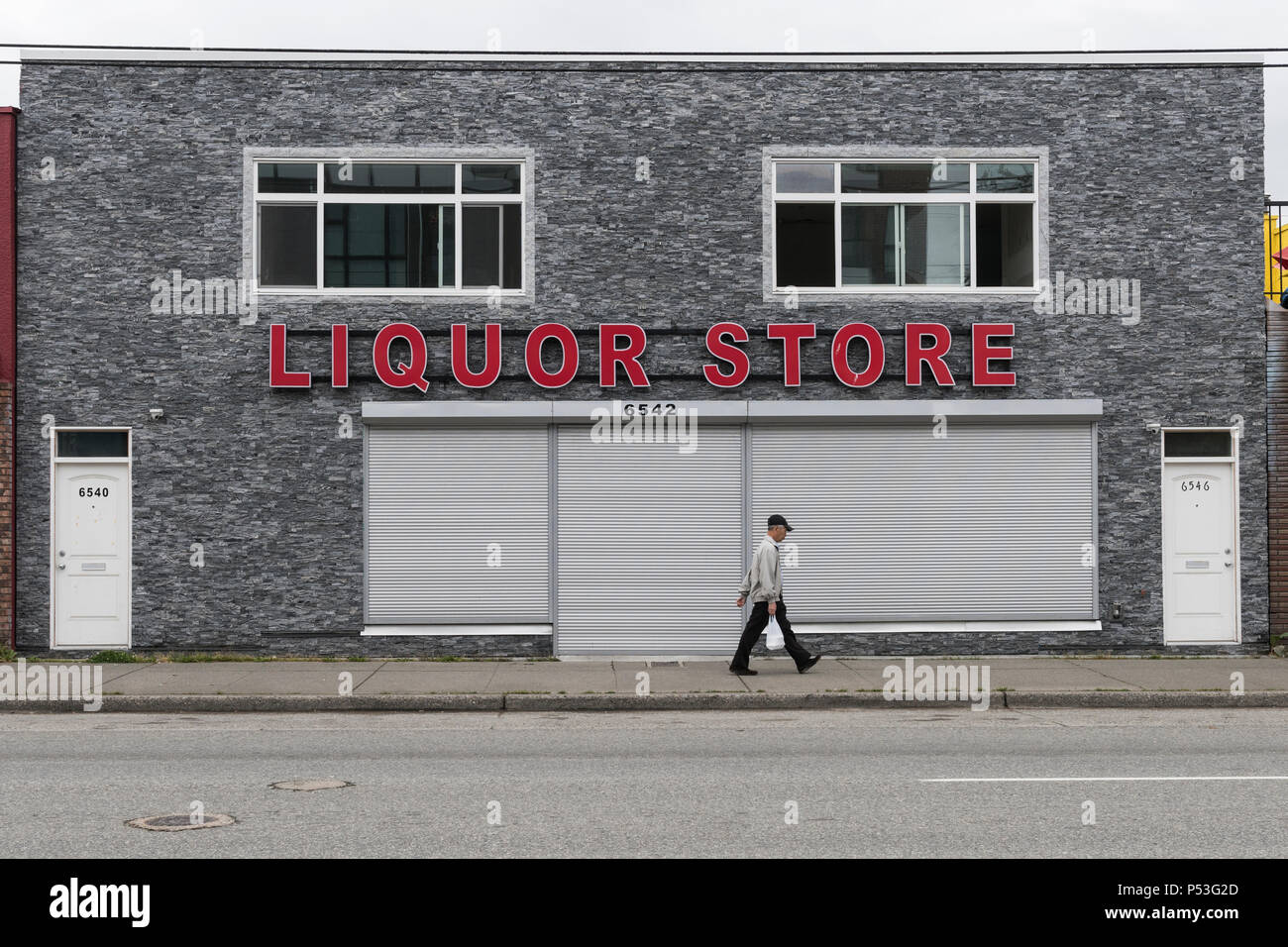 The large red letters spelling Liquor Store, on a grey stoned building, East Vancouver. Stock Photo