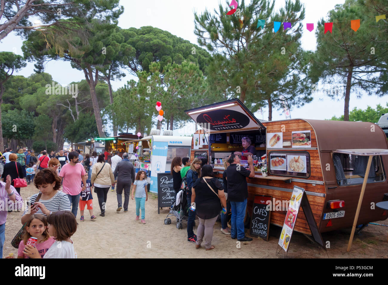 People with their families around a local festival with different food trucks, in the summer location for holidays of Stock Photo
