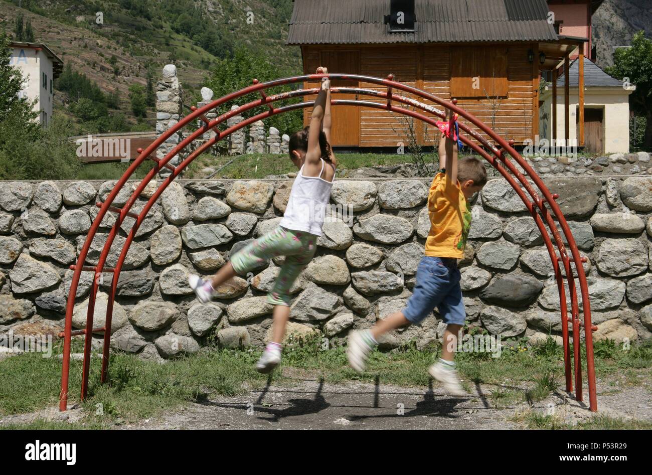 Niña de siete años y niño de seis jugando en una pasarela de un parque infantil. Benasque. Provincia de Huesca. Aragón. España. Stock Photo